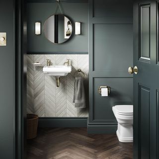 Small bathroom with dark green painted walls and white sanitaryware including metro tiles