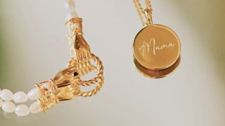Golden hand clasp on pearl necklace and gold mama pendant