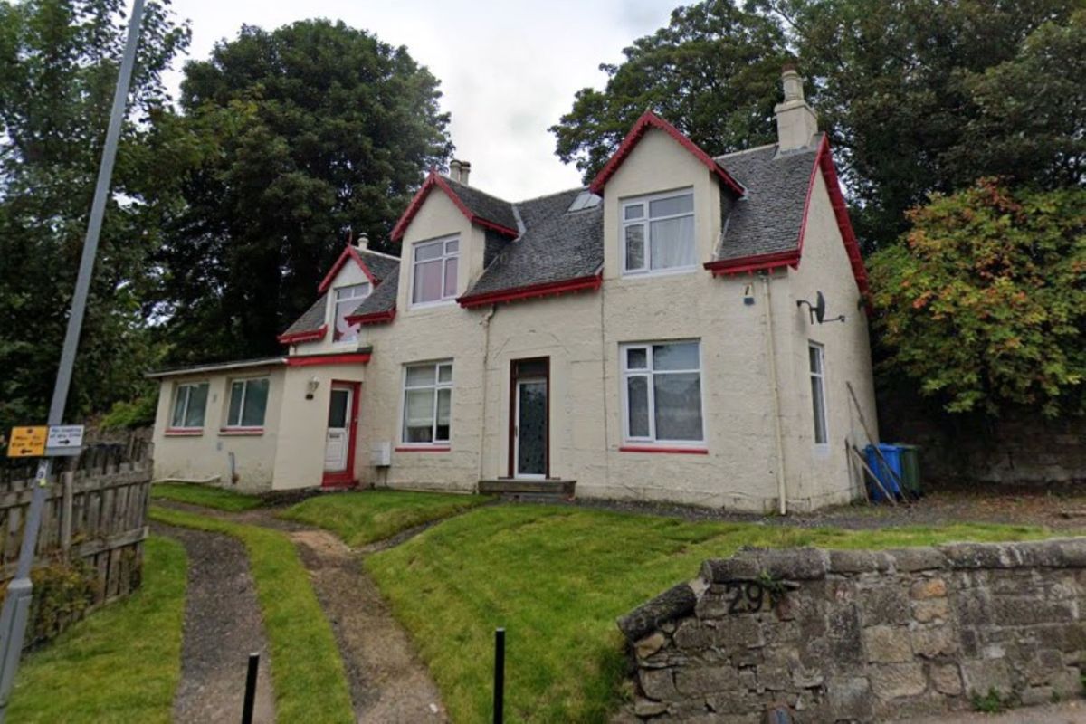 A white painted house with a stone wall in front