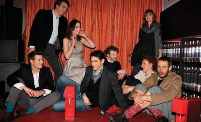 People sitting an talking in front of a red curtain 