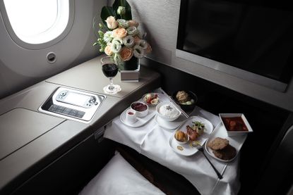 A multi-course meal spread out on a table in a first class cabin.
