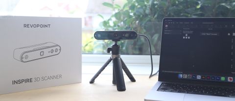 A Revopoint INSPIRE 3D Scanner on a desk, along with an object to scan and a laptop