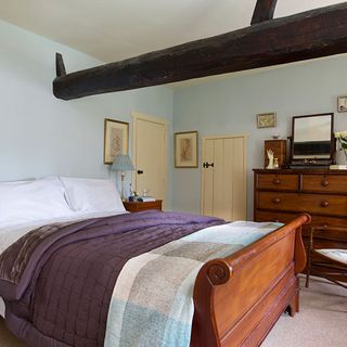 bedroom with wooden sleigh bed and cushions bluebell coloured walls