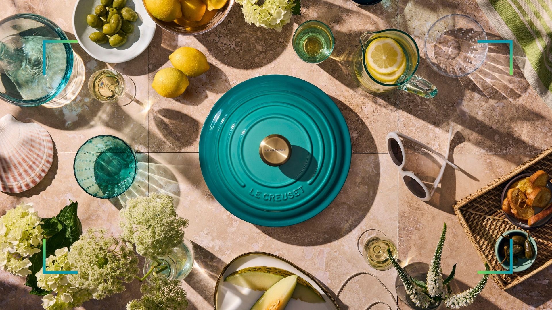 Le Creuset Bleu Riviera cast iron casserole on a table with lemons and green glassware