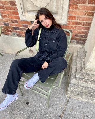 @tamaramory wears a denim jumpsuit, black roll-neck top and Converse