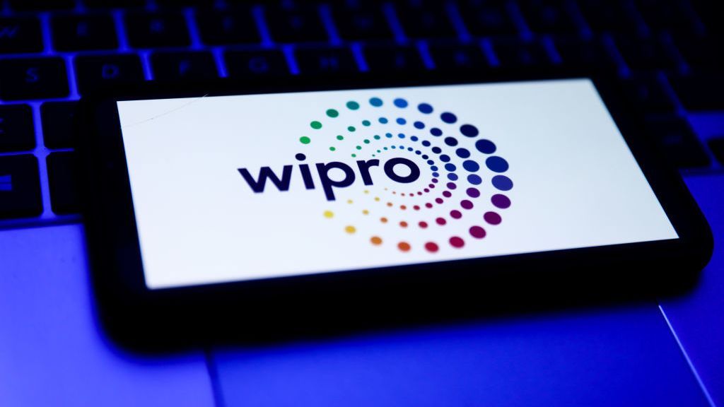 A smartphone resting on a laptop keyboard with the Wipro logo displayed on screen