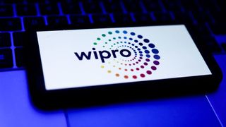 A smartphone resting on a laptop keyboard with the Wipro logo displayed on screen