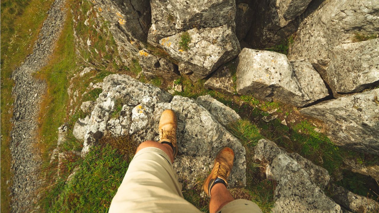 A man stands at the edge of a cliff.