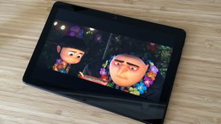 Amazon Fire HD 10 showing a scene from Despicable Me 3 on a wooden desk