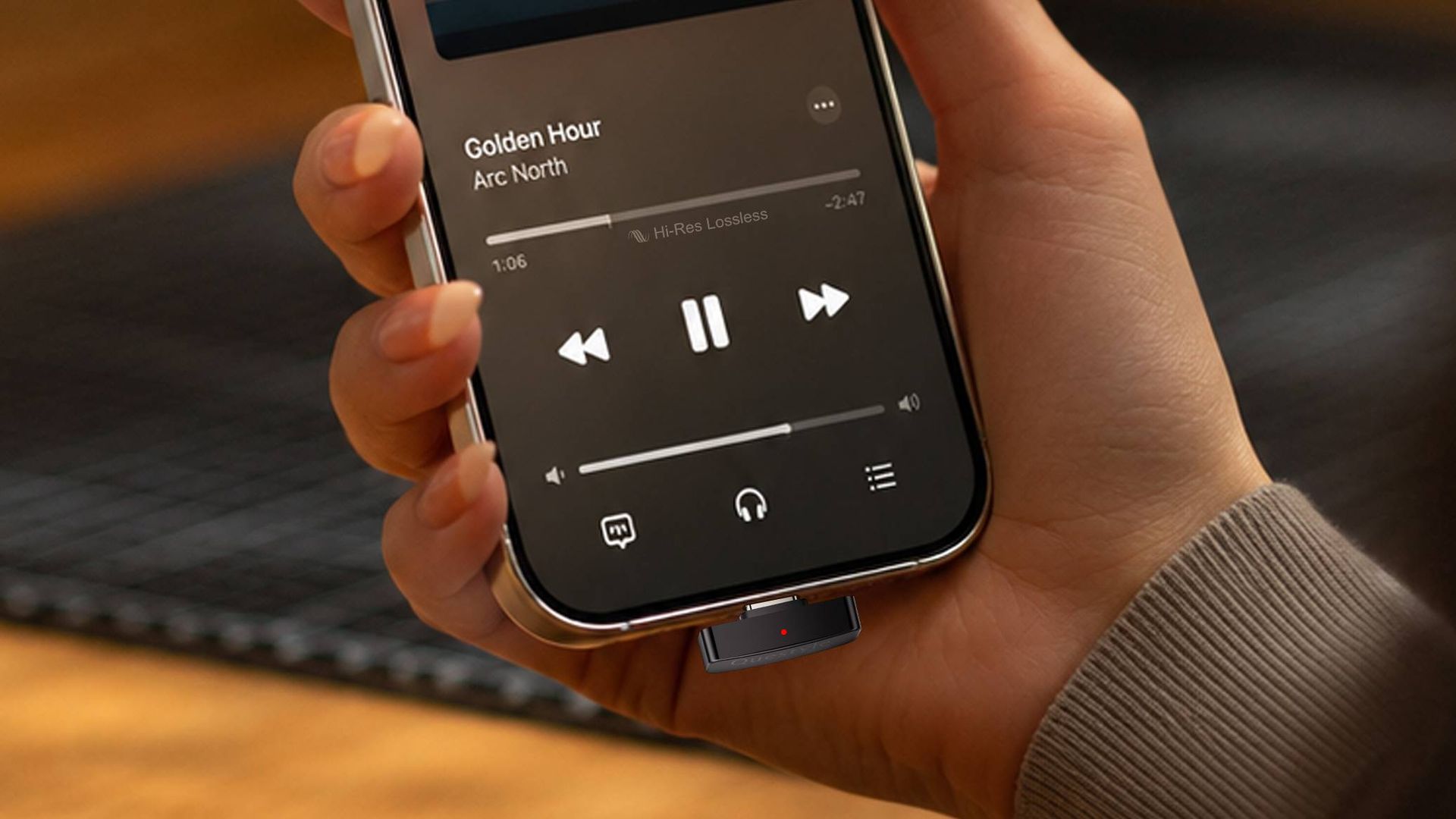 El Questyle QCC Dongle Pro 2, reproducido desde un reproductor de música, en la mano de una mujer.