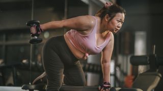 Woman lifting weights behind her hip using bench to kneel on
