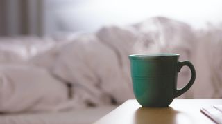 stay warm at night: cup of tea next to a bed