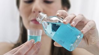 5 Causes of bad breath: image shows woman pouring mouthwash