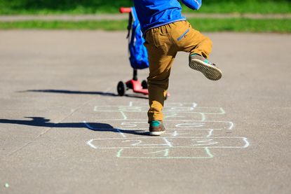A boy plays hopscotch on the playground.