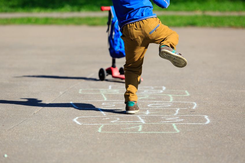 A boy plays hopscotch on the playground.