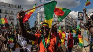 People waving flags of Senegal are seen during a protest in Madrid.