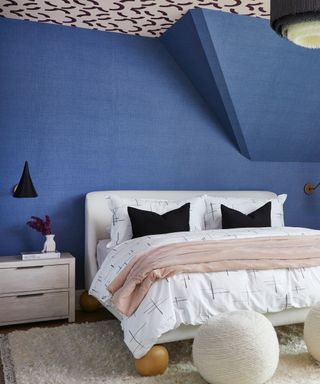 A bedroom with blue walls, a patterned ceiling, and a textured white rug