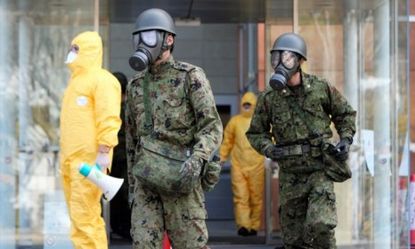 Japanese Self Defense Forces in anti-radiation gear search for evacuees near the nuclear plant.