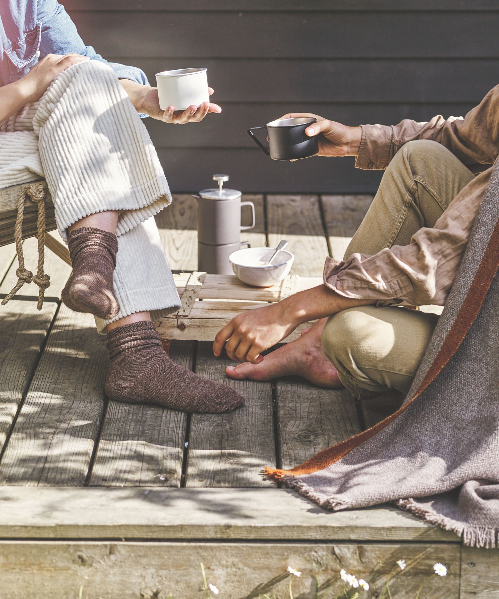 people drinking coffee on a deck with blankets