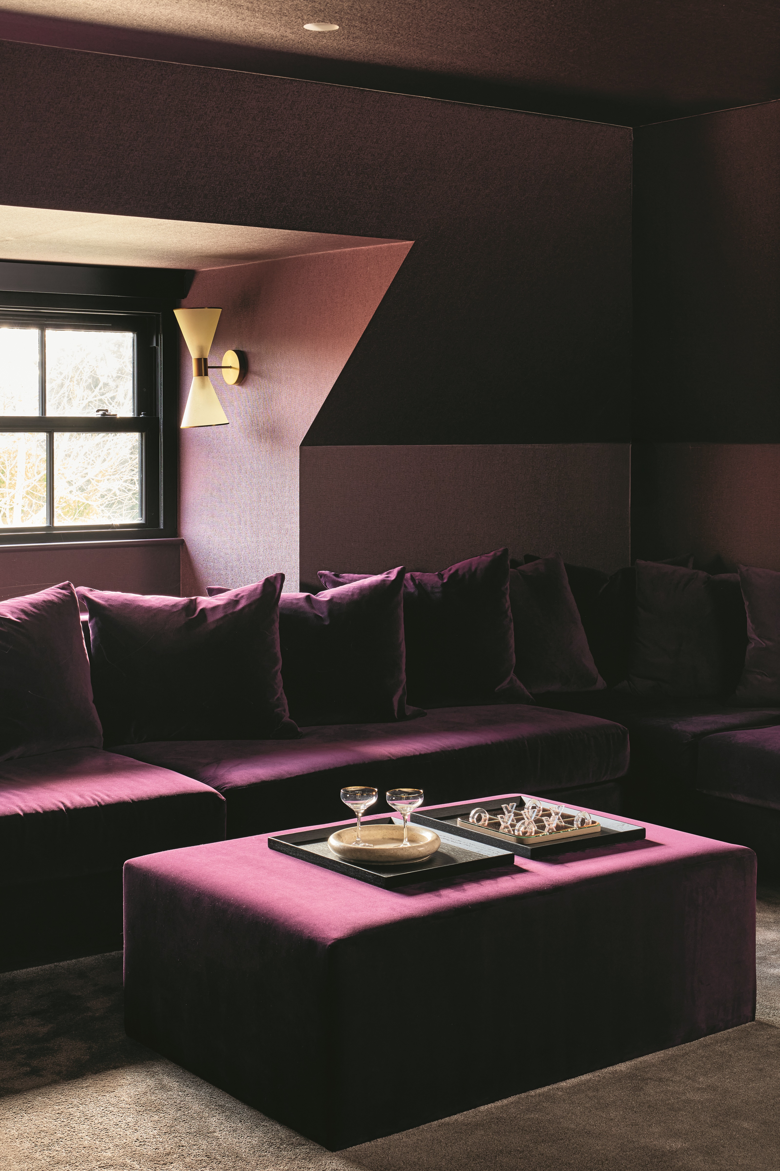 a dark pink cinema room design with a velvet sofa