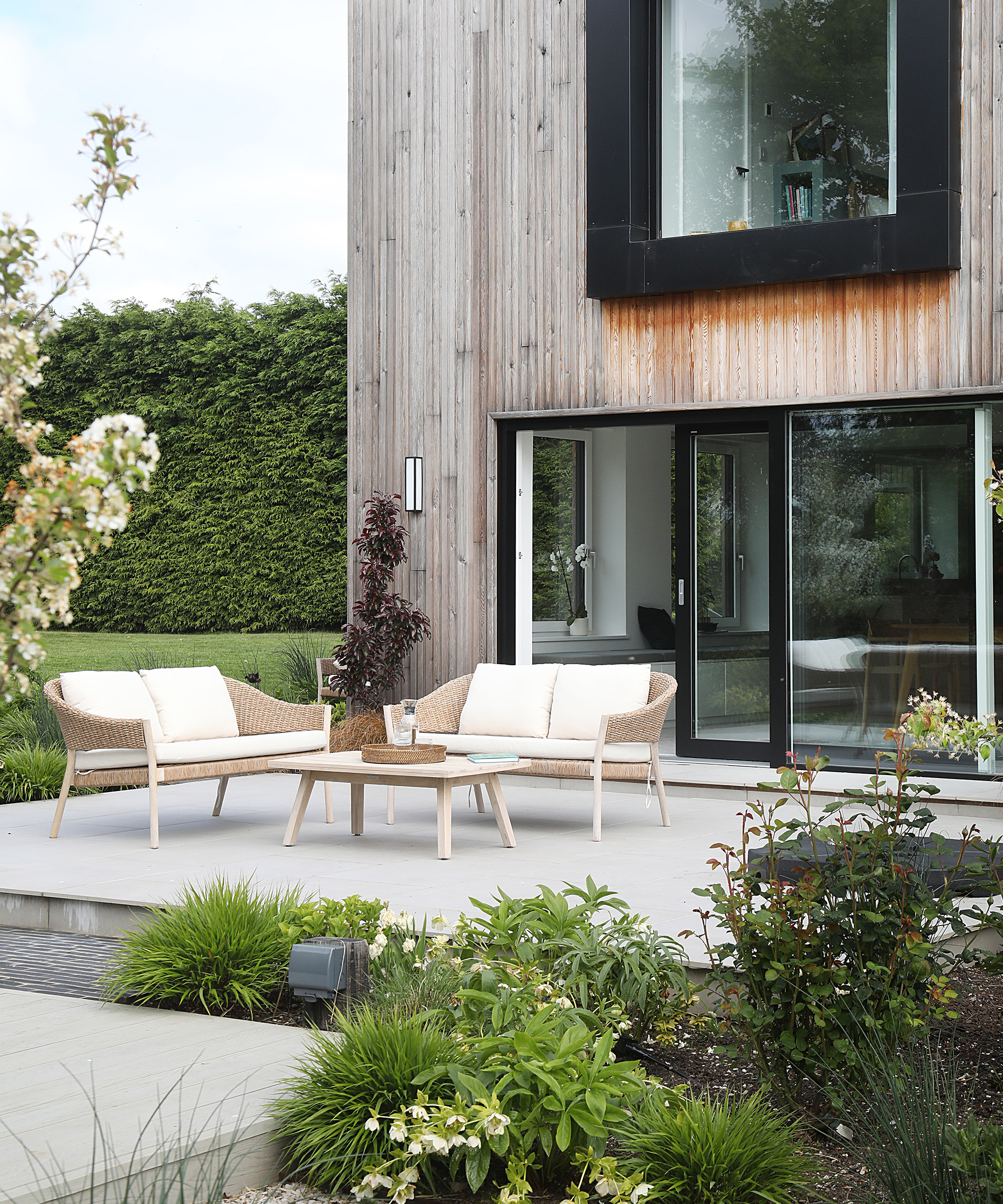 A light patio with garden sofa and coffee table set in front of sliding glass doors