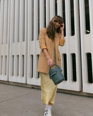 woman wearing yellow slip dress, blazer, and sneakers outfit