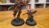Two fully painted Warhammer Kill Team miniatures on a wooden table