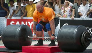 A large man deadlifts a huge barbell