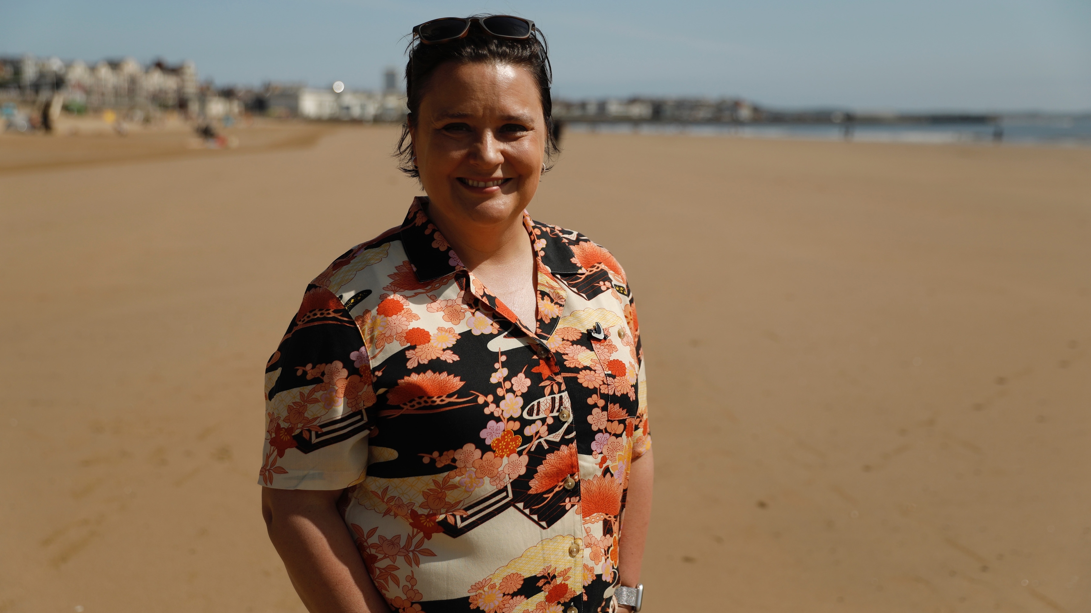 Susan in an orange shirt and standing on the beach