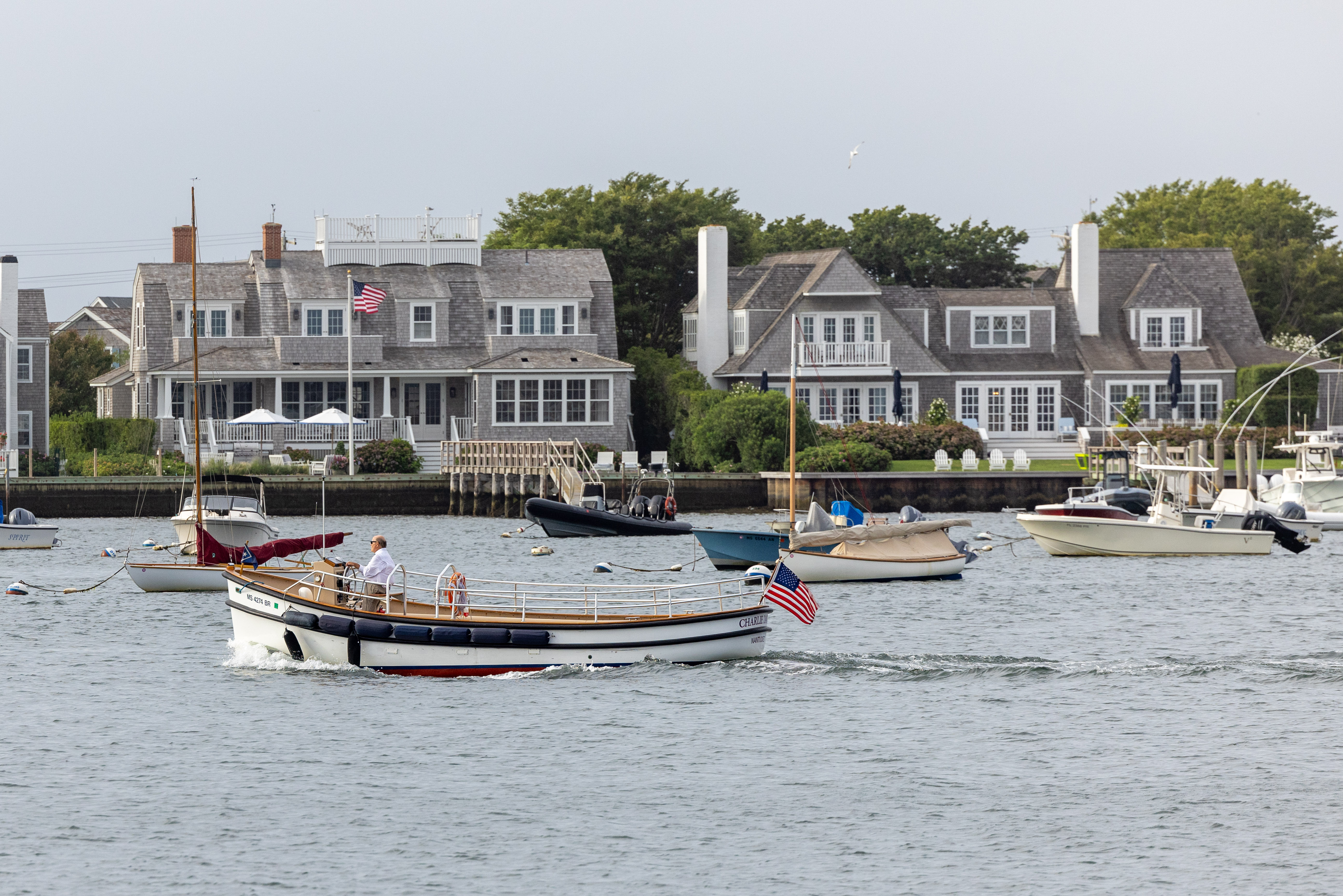 White wooden sailboat motoring in front of clapboard houses