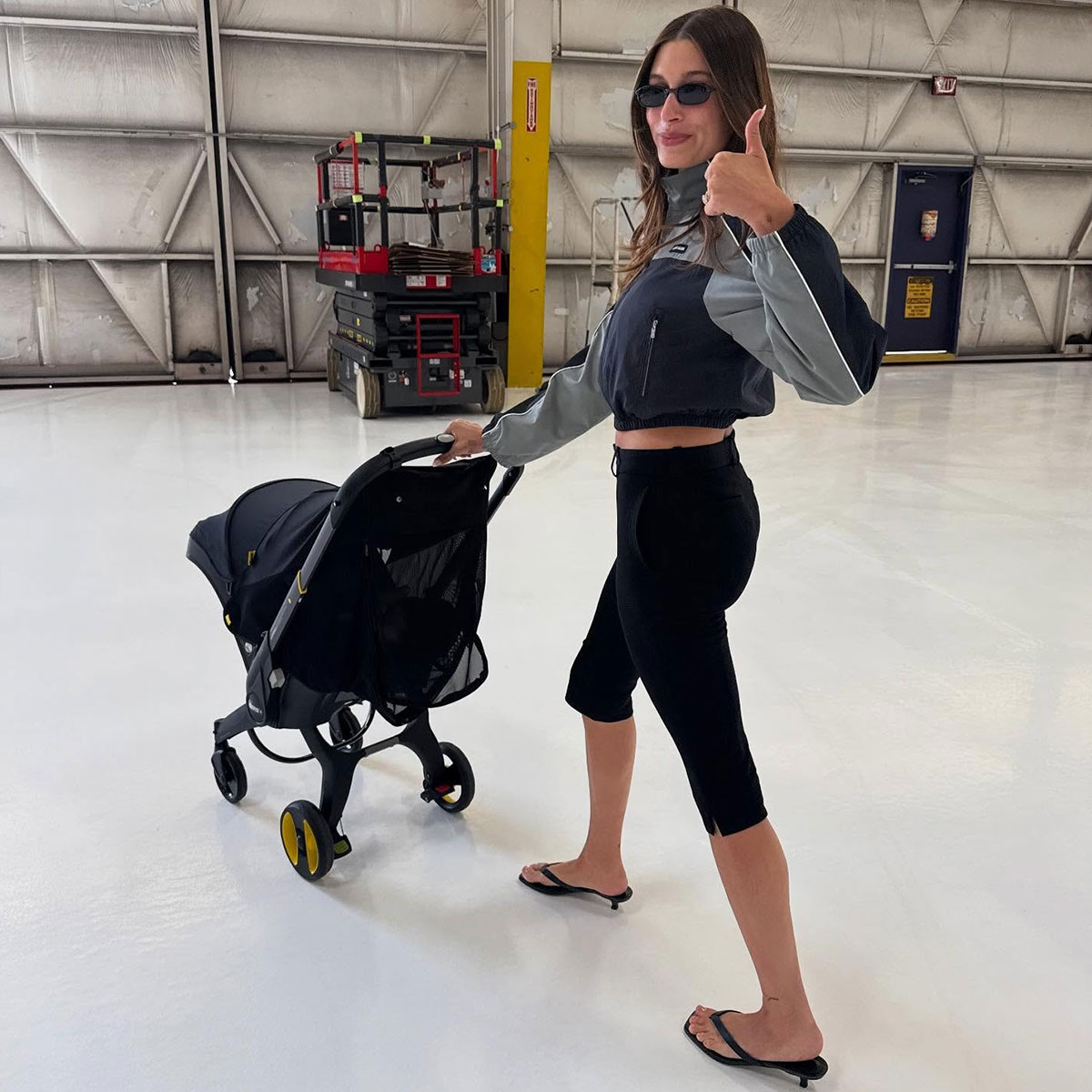 @haileybieber pushing stroller in cropped windbreaker and capri leggings 