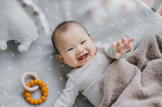 Portrait of a lovely Asian baby girl smiling sweetly while lying on the crib