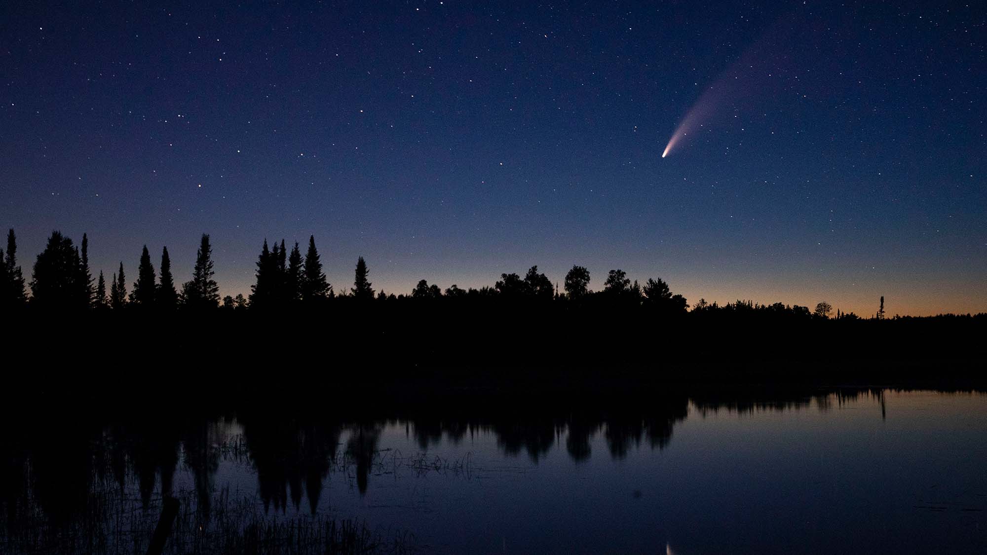 Комета NEOWISE пронеслась по ночному небу над озером Вулф в Бримсоне, штат Миннесота.