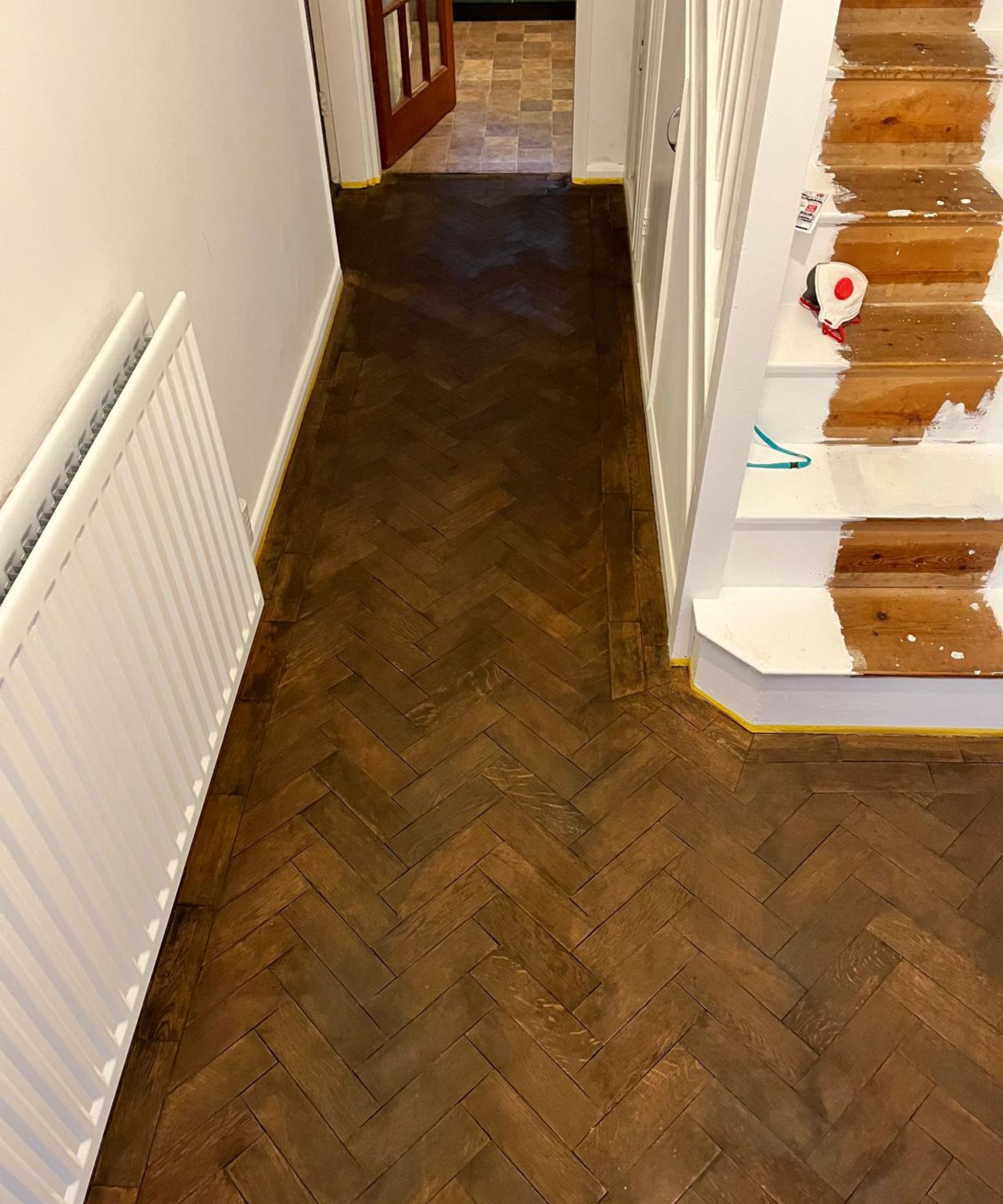 A vintage parquet floor being renovated via sanding and the application of wood dye