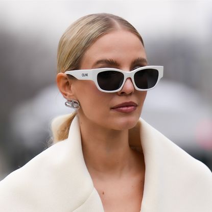 eyebrow shapes - Leonie Hanne wears white sunglasses from Celine, silver and rhinestones earrings from Balenciaga, a white latte oversized long belted coat, outside Coperni, during Paris Fashion Week - Womenswear F/W 2022-2023, on March 03, 2022 in Paris, France