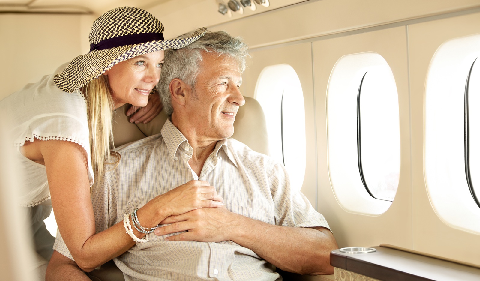 A wealthy older couple on a private plane, looking out the window.