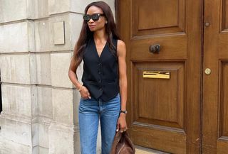 Woman wearing a black waistcoat and jeans.