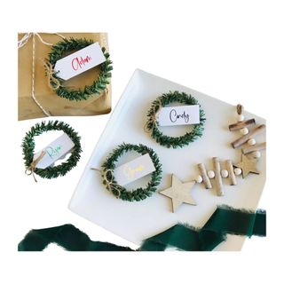 Christmas tree place cards on white plates and a brown present