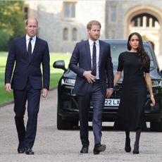 Prince WIlliam walking next to Prince Harry and Meghan Markle