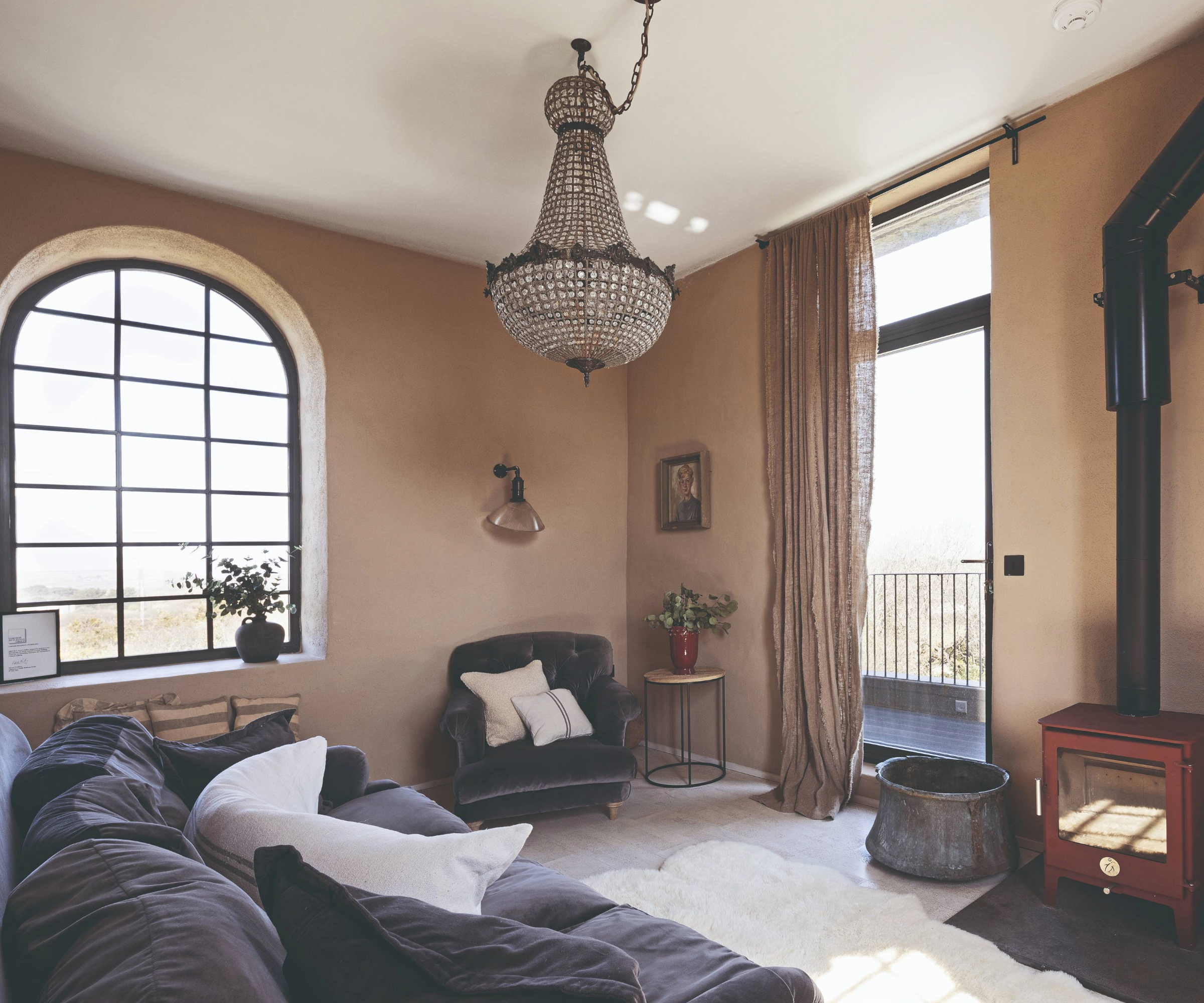 Living room with large arched window and log burner
