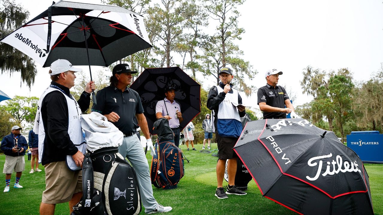 Pat Perez, Jhonattan Vegas and Ian Poulter huddle under umbrellas at The Players Championship