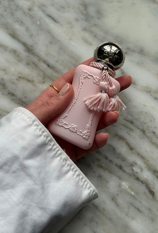 Hand holding a bottle of Parfums De Marly Delina perfume