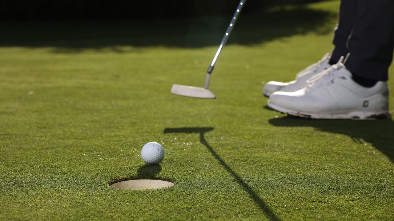 Close up of a ball being putted into a hole