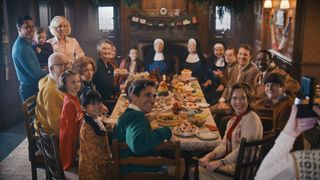The cast of Call the Midwife sit around a Christmas table.