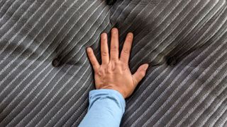 A hand pressing down on the Beautyrest Black K-Class Plush Pillow Top mattress