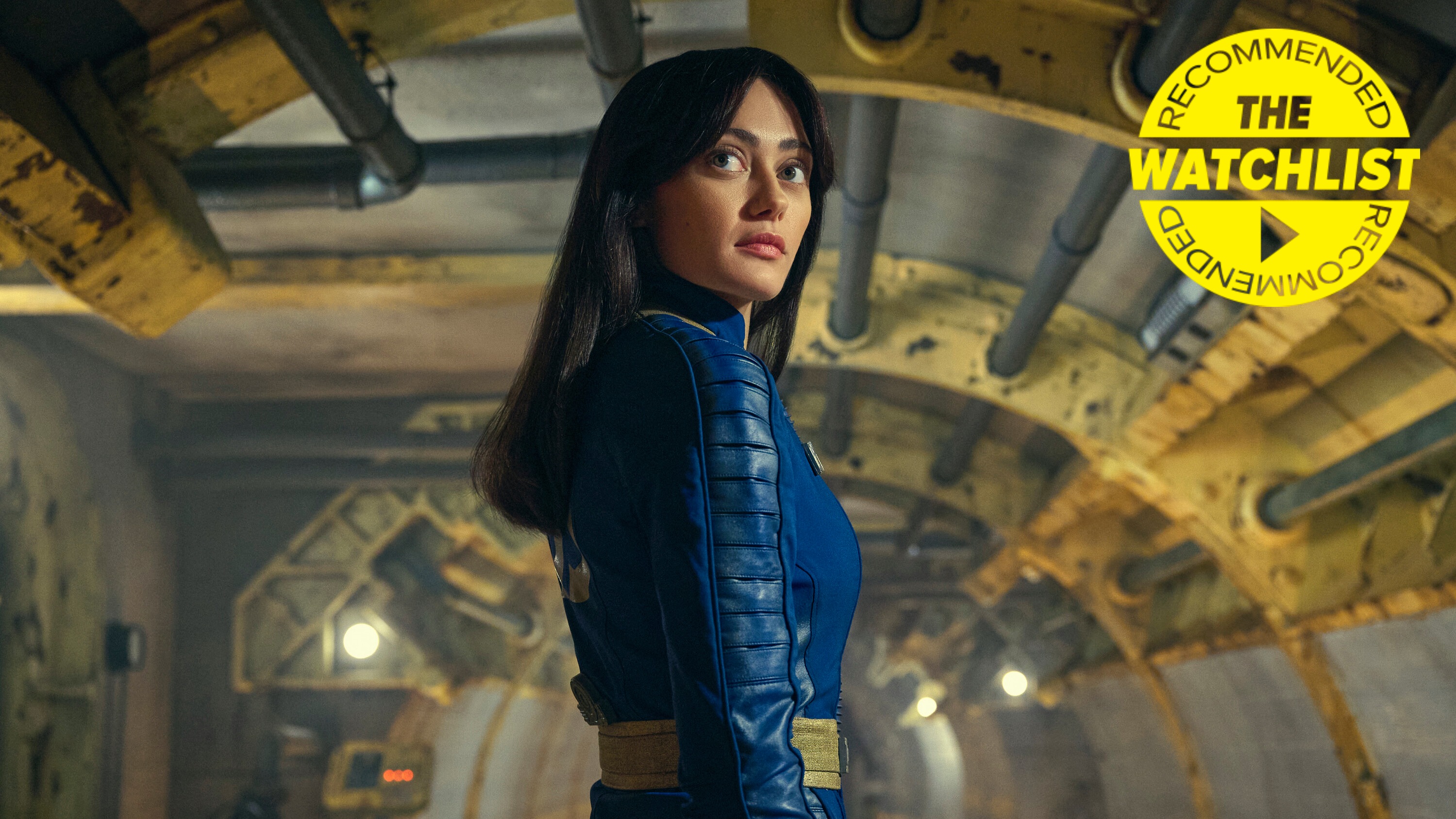 Lucy (Ella Purnell) in Vault 33 in the Fallout TV show, with our yellow Watchlist Recommended badge in the top-right corner of the image