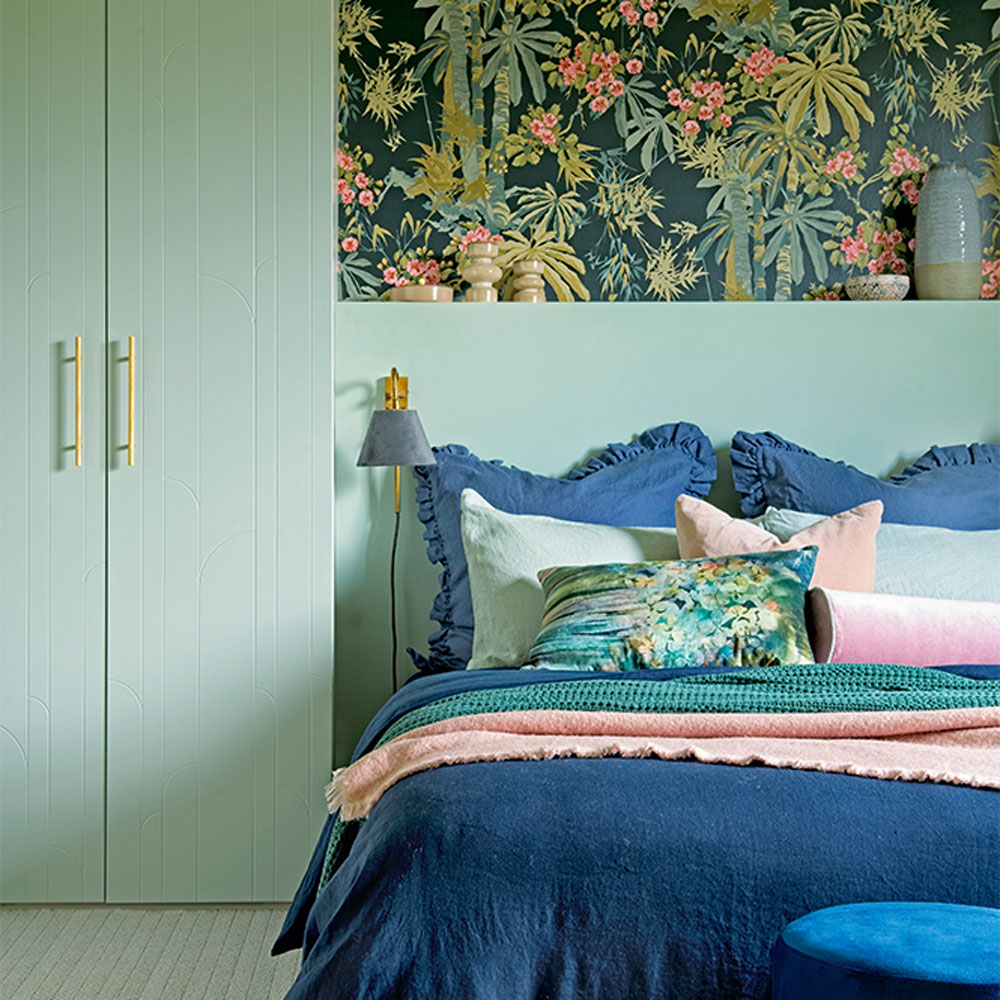 green bedroom with blue bed and tropical picture