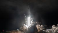 a white rocket lifts off above a plume of fire and smoke