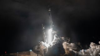 a white rocket lifts off above a plume of fire and smoke