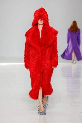 Woman in fluffy red coat and hat on MSGM runway